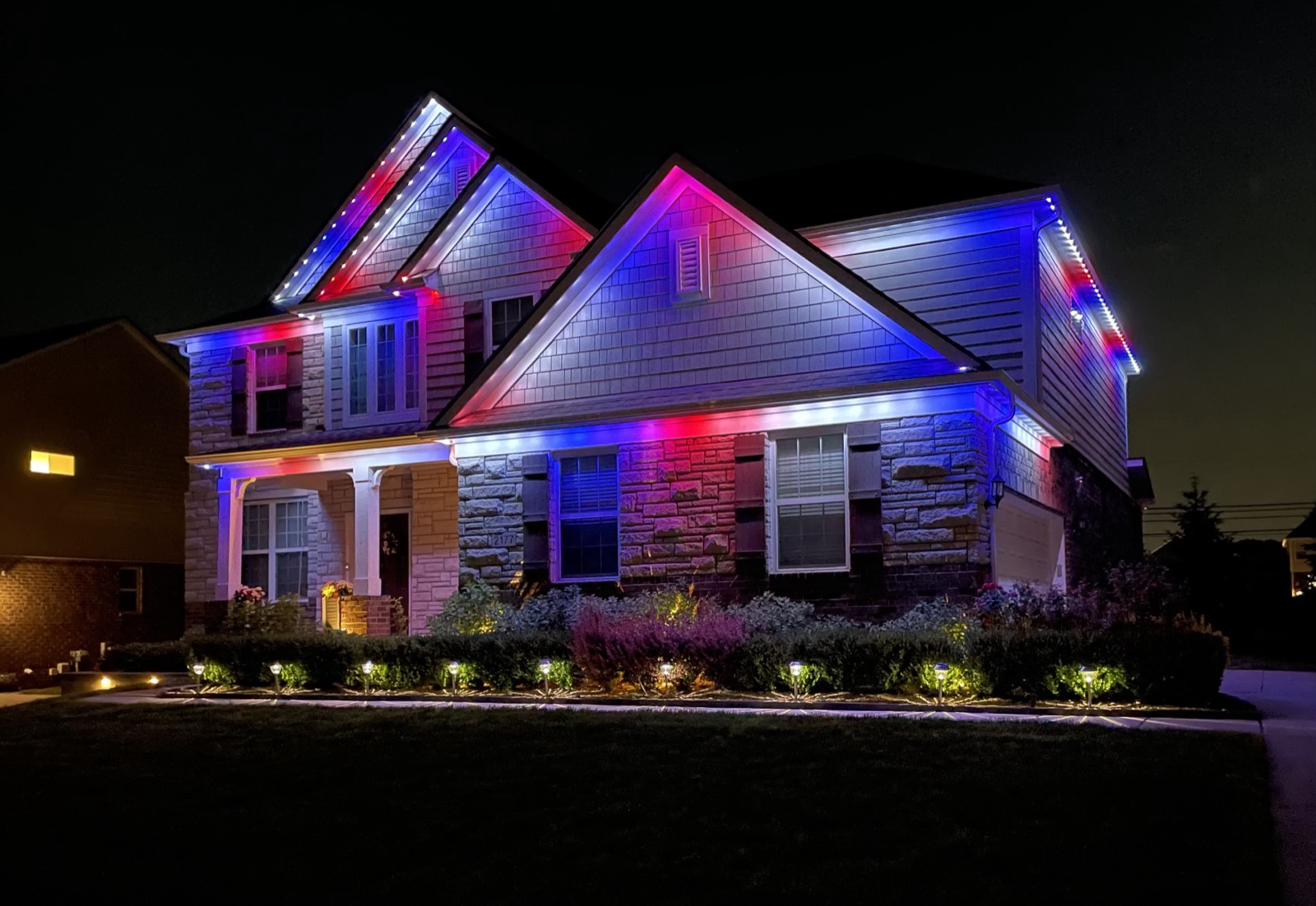 Luxury Michigan home with permanent roofline lighting at dusk